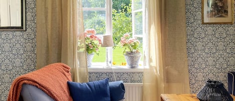 A cozy room with a sofa, a wooden table, and a window with curtains.