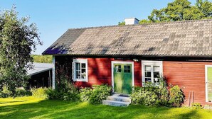A red wooden house with a green door, white windows, and a grey roof. - 4 Star Holiday Home in Osthammar (Osthammar)