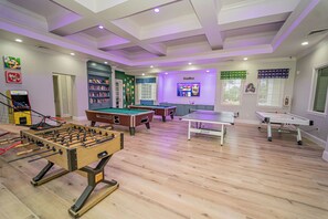 Uma sala de lazer com mesa de futebol de mesa, sinuca e pingue-pongue.