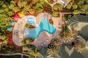 Vista aérea de um resort com piscina, espreguiçadeiras e palmeiras.