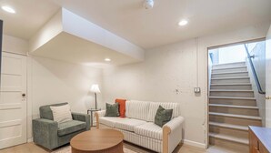 Un salon comprenant un canapé, un fauteuil, une table basse et un escalier.