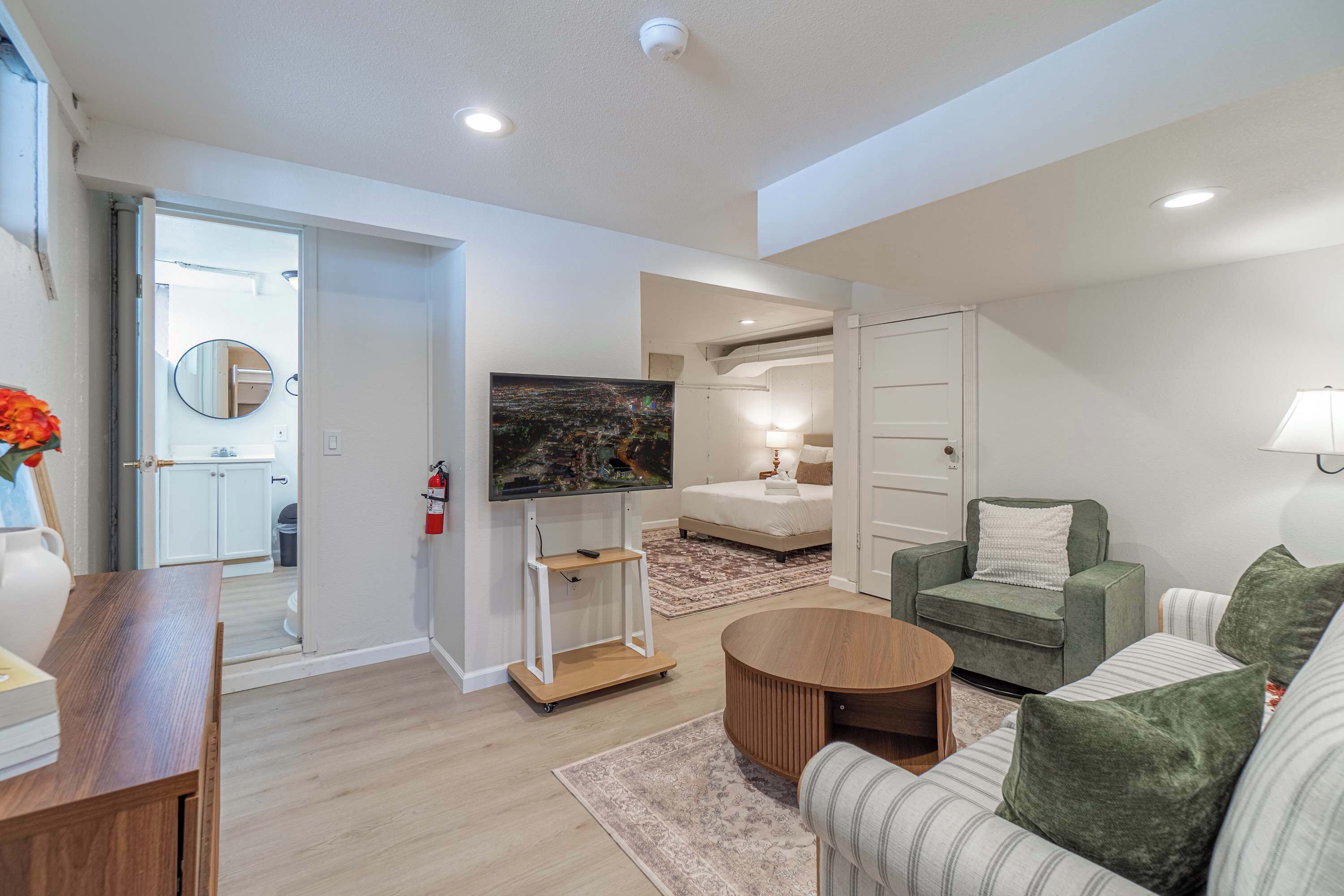 A modern living room with a flat-screen TV, a sofa, a coffee table, and a dining area.