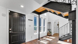 A modern interior with a black door, wooden flooring, and a staircase with a black railing. - Reno Retreat - 3BR Oasis w Swim Spa, Hot Tub (Reno)