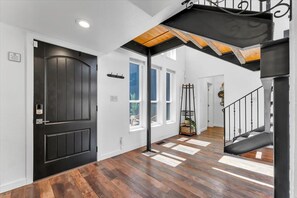 A modern interior with a black door, wooden flooring, and a staircase with a black railing. - Reno Retreat - 3BR Oasis w Swim Spa, Hot Tub (Reno)