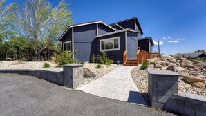 A modern two-story house with a stone pathway leading to the entrance, surrounded by a landscaped garden with rocks and trees. - Reno Retreat - 3BR Oasis w Swim Spa, Hot Tub (Reno)