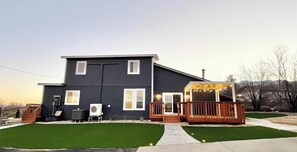 Ein zweistöckiges Haus mit einer Terrasse, einer überdachten Veranda und einem gepflegten Rasen.