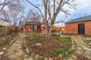 A backyard with a tree, a brick building, and a stone pathway. - The Luxury Brick Home Mature Yard Chef Kitchen (Reno)