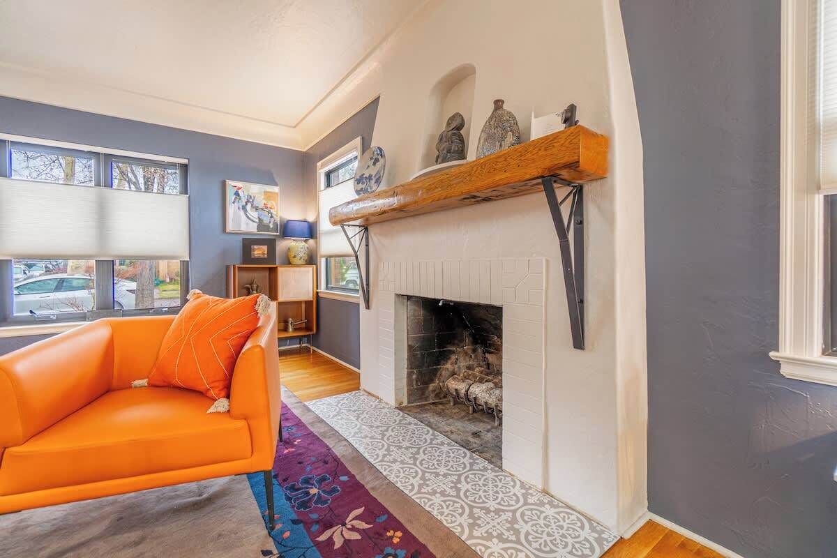Una sala de estar con chimenea, un sofá y una alfombra estampada.