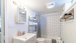 Een badkamer met een wit wastafelmeubel, toilet en douche.