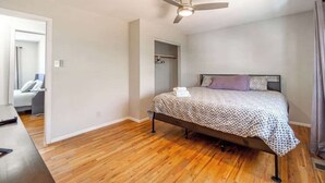 A bedroom with a bed, a ceiling fan, a wooden floor, a closet, and a bathroom visible through an open door. - Spacious Pet-friendly Retreat 4br, Grill, 5 Beds (Reno)