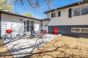 Ein Haus mit einer Terrasse, auf der sich ein Tisch und Stühle befinden, einer roten Tür und einer Garage.