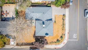 An aerial view of a residential area with a house featuring a sloped roof, a fenced yard, and a stop sign on the street. - Spacious Pet-friendly Retreat 4br, Grill, 5 Beds (Reno)