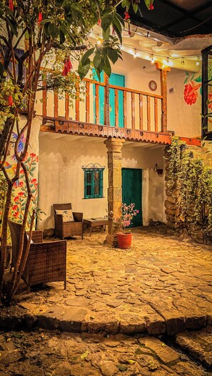 A courtyard with a stone floor, a wooden balcony, a chair, and a potted plant. - Heyyy Cusco (Cusco)