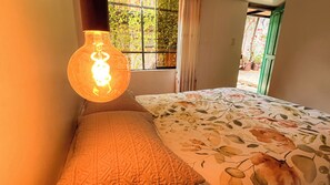 Une pièce avec un lit, un luminaire suspendu et une fenêtre donnant sur un paysage verdoyant.