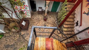 A staircase leading to a stone-floored courtyard with a view of a building's interior.