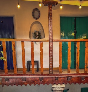 A wooden balcony with a railing, a small table, and a potted plant. - Heyyy Cusco (Cusco)
