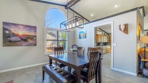 A dining area with a large table, benches, and a view of the kitchen. - Modern Getaway for 11- Hot Tub, Games, Gym (Reno)