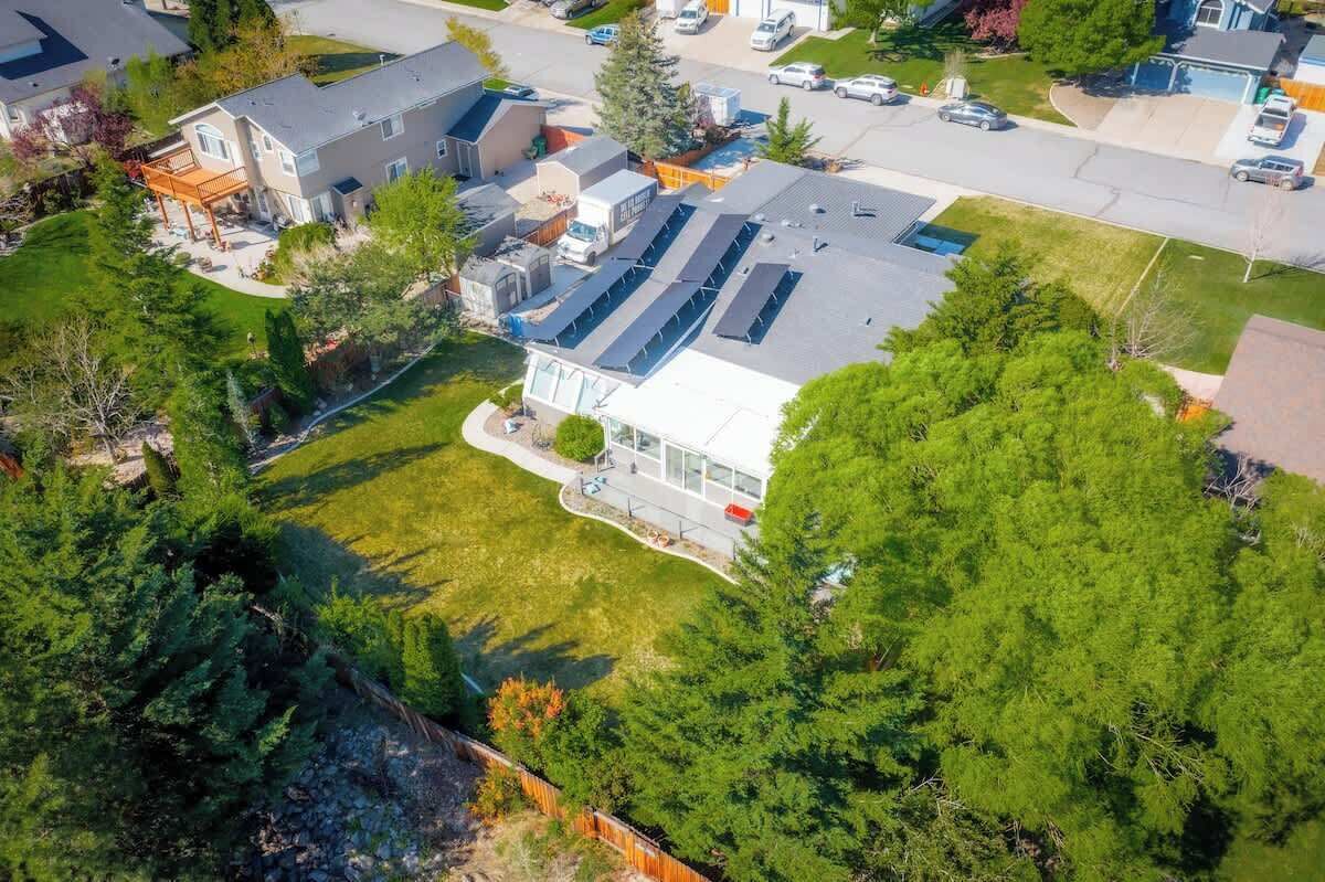 An aerial view of a residential area with houses, a driveway, and a large green space.