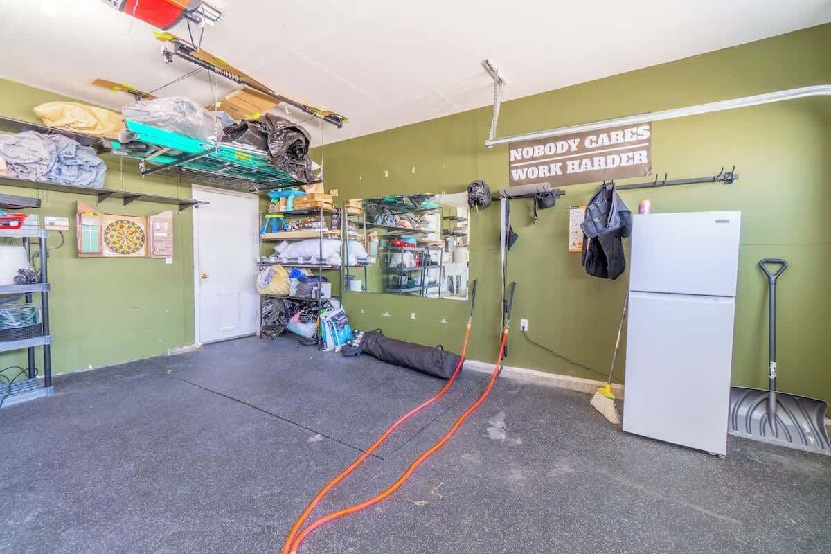 A room with a green wall, a white door, and various items like a helmet, bags, and a sign that reads 'NOBODY CARES WORK HARDER'.