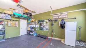 A room with a green wall, a white door, and various items like a helmet, bags, and a sign that reads 'NOBODY CARES WORK HARDER'. - Modern Getaway for 11- Hot Tub, Games, Gym (Reno)