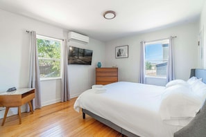 A bedroom with a bed, a desk, a dresser, and a window with curtains. - Midtown Sanctuary w Pac-man! (Reno)