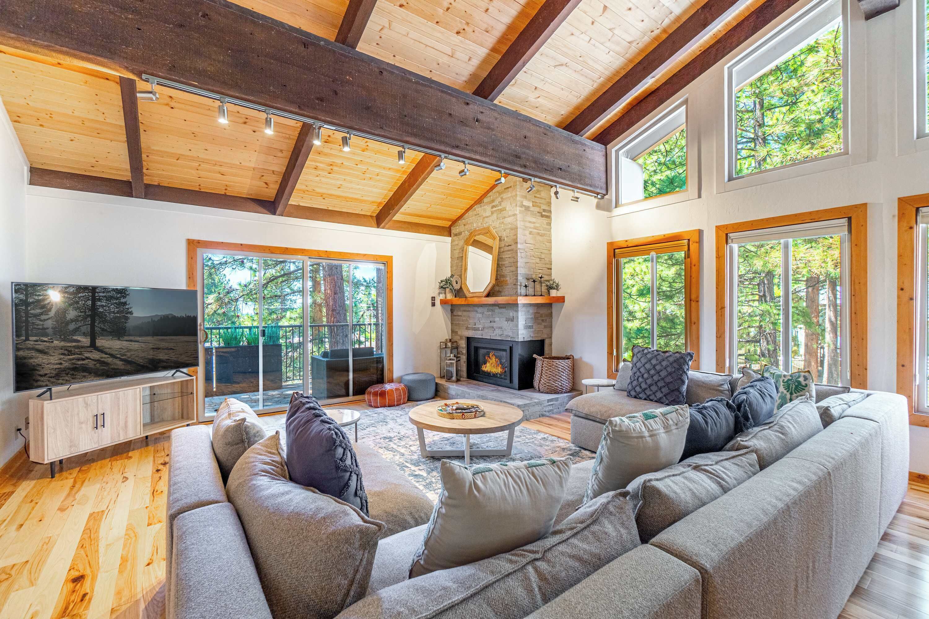 A spacious living room with a large sofa, a fireplace, and large windows.