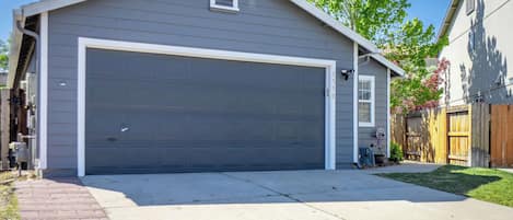A single-story house with a large garage door, a brick driveway, and a wooden fence.