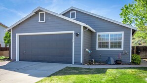 A residential house with a garage, a small window, and a well-maintained lawn. - Large Group Escape, 5 Beds, Pets Welcome (Reno)