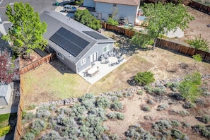 A residential property with a solar panel roof, a patio with outdoor furniture, and a landscaped yard with shrubs. - Large Group Escape, 5 Beds, Pets Welcome (Reno)