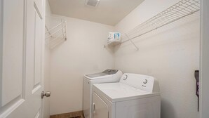 A laundry room with a washer and dryer, metal shelves, and a door. - Large Group Escape, 5 Beds, Pets Welcome (Reno)