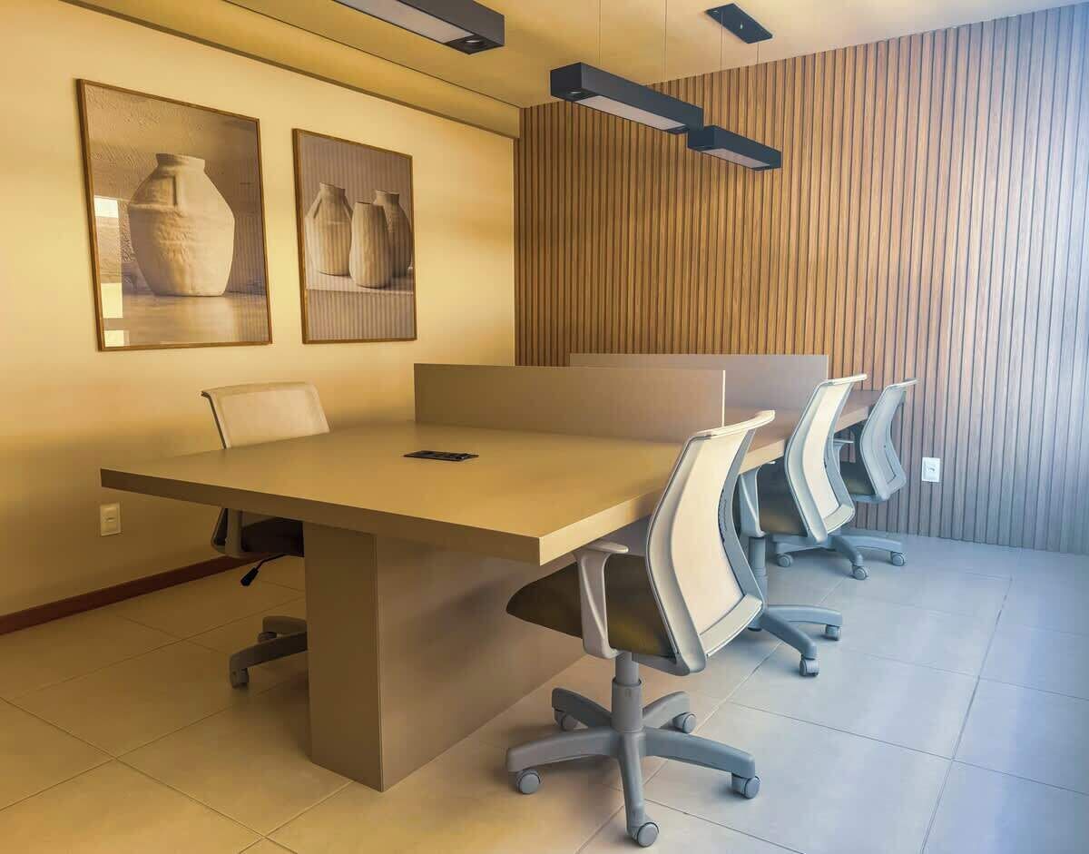 Uma sala de conferência com uma mesa comprida, quatro cadeiras e duas fotografias emolduradas na parede.
