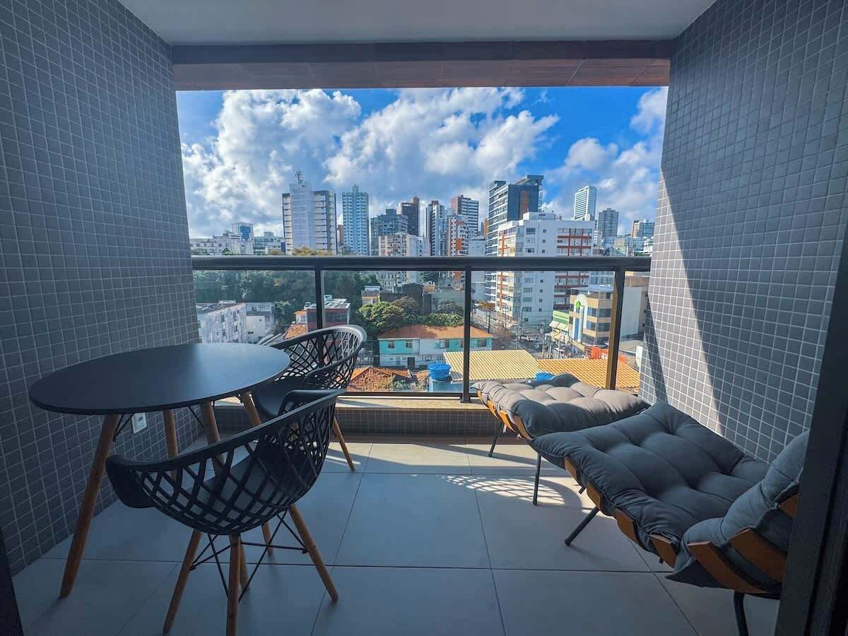 Uma varanda com mesa e cadeiras, um sofá e vista para a cidade.