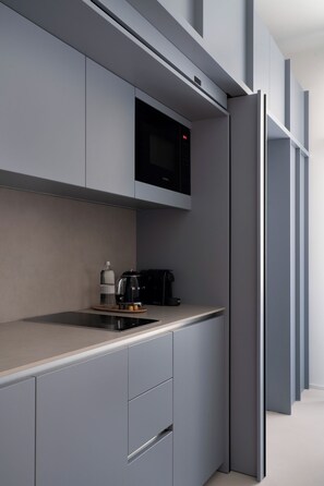Eine moderne Küche mit grauen Schränken, einer eingebauten Mikrowelle, einer Kaffeemaschine und einem Wasserkocher auf der Arbeitsfläche.