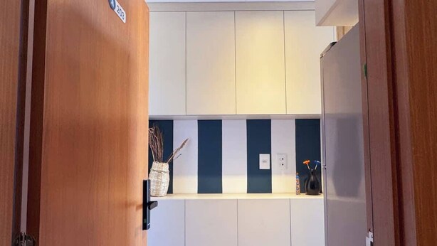 A modern kitchen with wooden cabinets, a countertop, and a built-in oven. - Studio c/ Varanda Vista Mar • Stella Maris & Farol (Salvador)