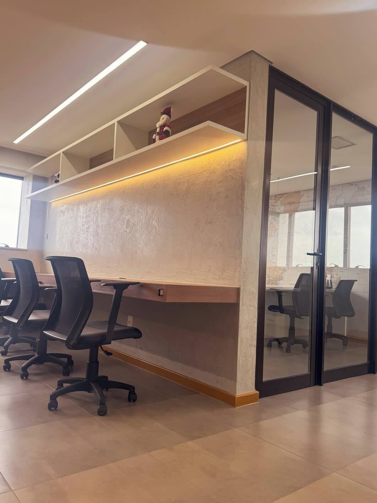 A modern office space with a long table, multiple office chairs, and a glass partition wall.