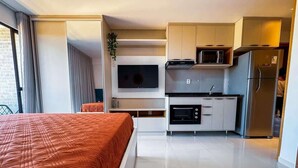 A hotel room with a bed, kitchenette, and a TV. - Studio c/ Varanda Vista Mar • Stella Maris & Farol (Salvador)