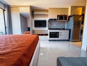 A hotel room with a bed, kitchenette, and a TV. - Studio c/ Varanda Vista Mar • Stella Maris & Farol (Salvador)