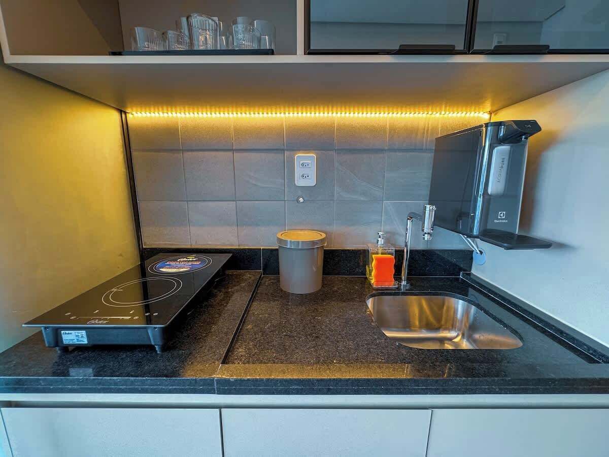 A modern kitchen with a built-in induction cooktop, a stainless steel sink, and a compact refrigerator.