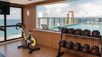 Un gimnasio con equipo de ejercicio, una bicicleta y un soporte para pesas con lastres.