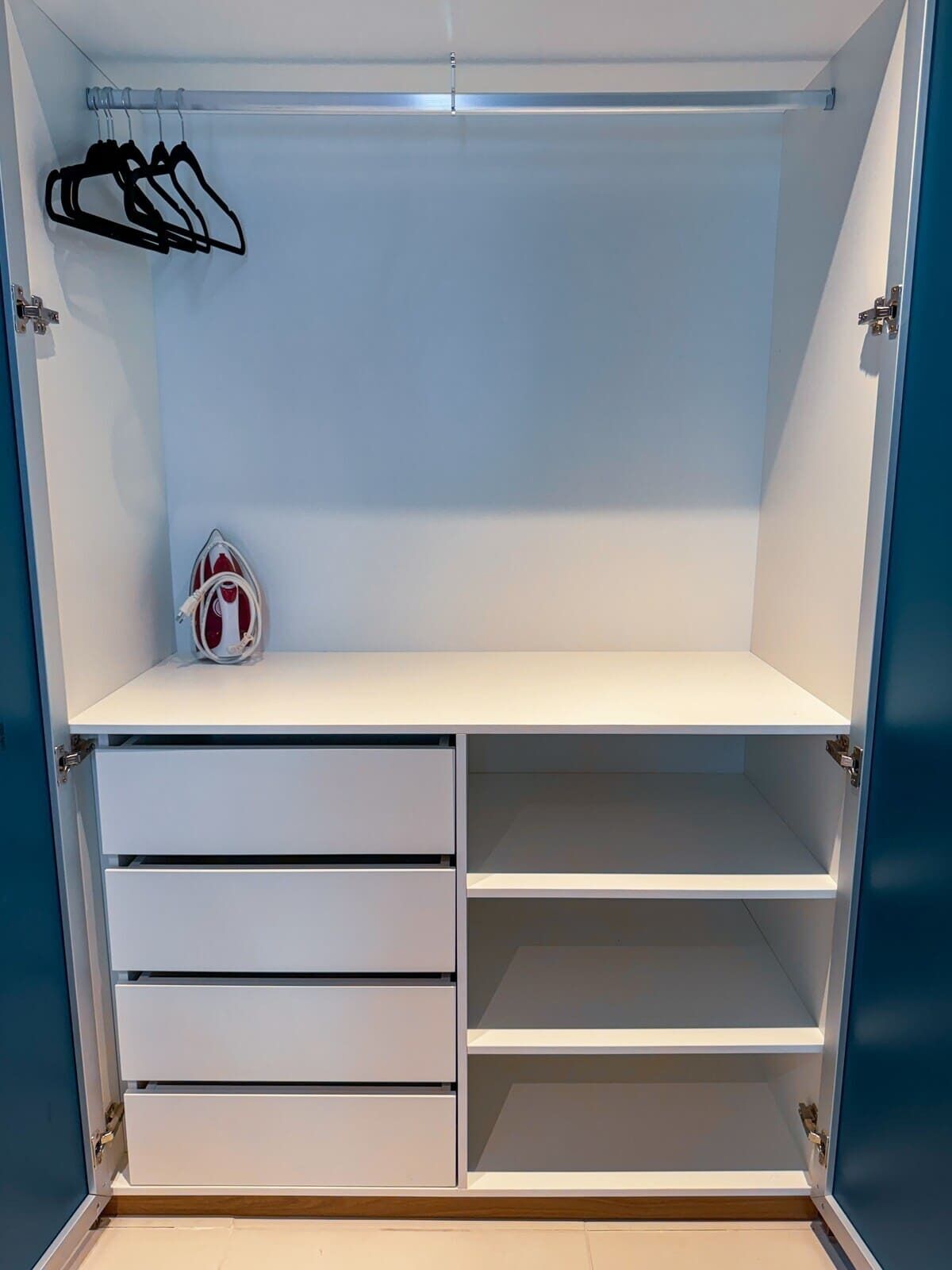 Um closet amplo com prateleiras abertas, uma barra para pendurar roupas e gavetas.