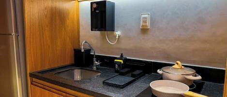 A compact kitchen with a sink, a stove, and a countertop.