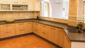 A kitchen with wooden cabinets, a black countertop, and a tiled backsplash. - Villa La Vida Antas by Ruralidays (Almería)