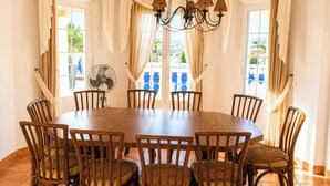 A dining area with a round wooden table surrounded by chairs, a fan, and curtains. - Villa La Vida Antas by Ruralidays (Almería)