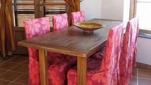 A dining table with a bowl centerpiece, surrounded by chairs with floral upholstery.