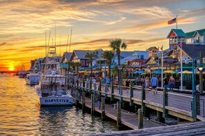 A waterfront pier with boats docked, a wooden walkway, and buildings with signs for local businesses. - Fort Walton 3BR | 2 Kings + Fenced Yard | Pets OK (Fort Walton Beach)