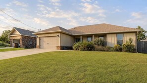 A single-story house with a garage, a front lawn, and a wooden fence. - Gulf Breeze Oasis: Hot Tub, Pet-Friendly, Beach (Gulf Breeze)