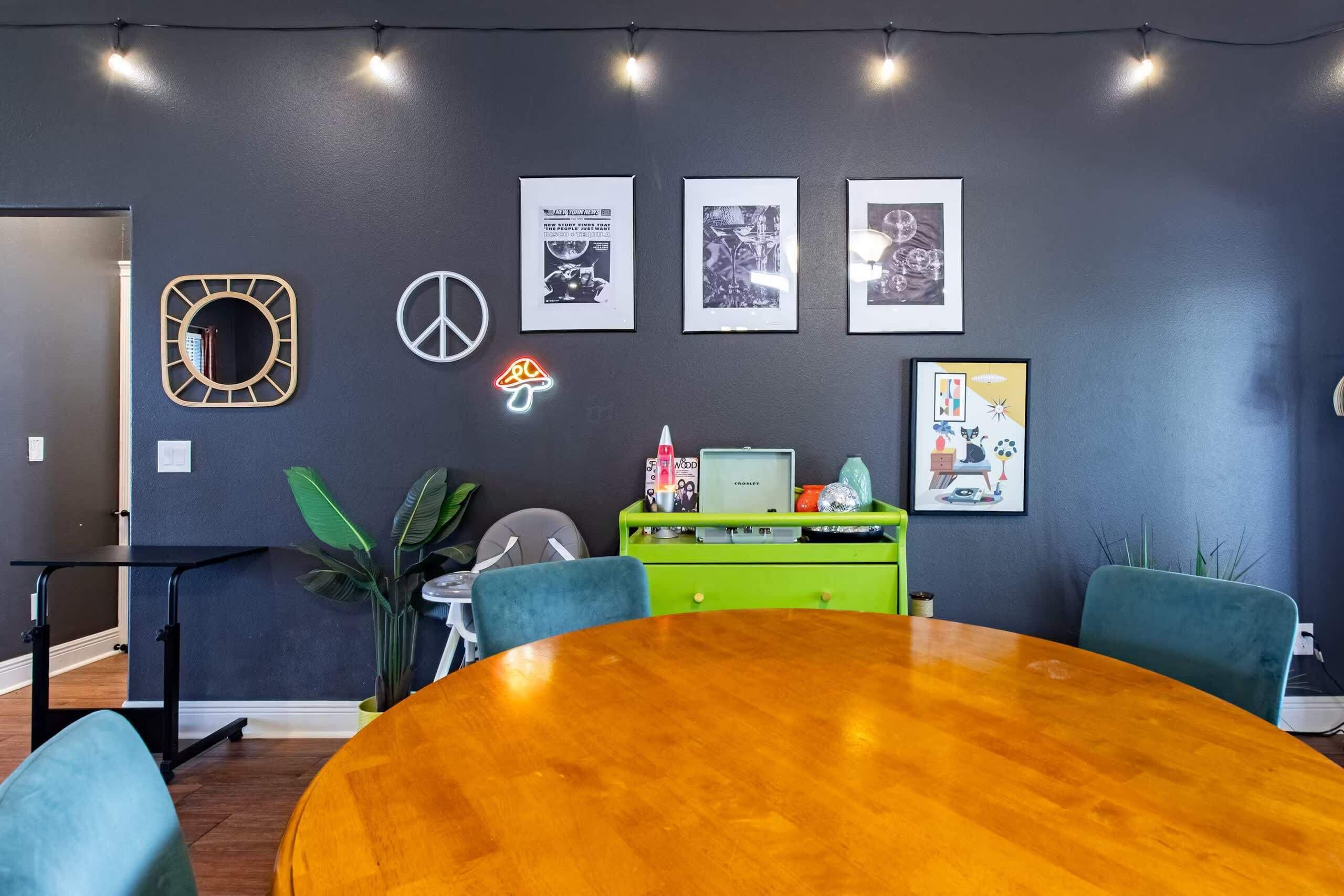 A conference room with a wooden table, chairs, a green desk, and framed pictures on the wall.