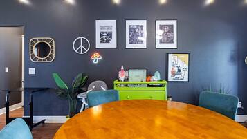 A conference room with a wooden table, chairs, a green desk, and framed pictures on the wall.