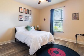 A bedroom with a bed, a window with blinds, a ceiling fan, and wall art. - Gulf Breeze Oasis: Hot Tub, Pet-Friendly, Beach (Gulf Breeze)