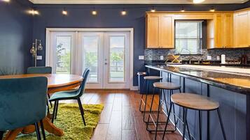 A modern kitchen with a bar area, wooden cabinets, and a dining set.